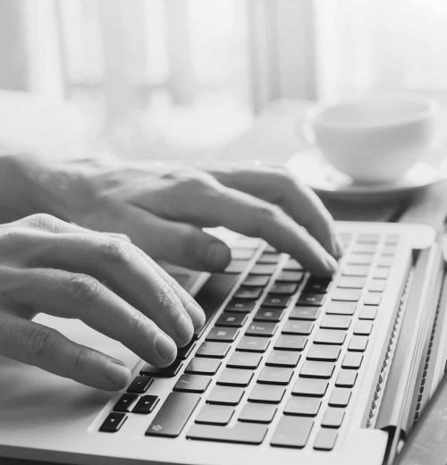 close up of hands of a creahive employee working on computer, man using internet and social media